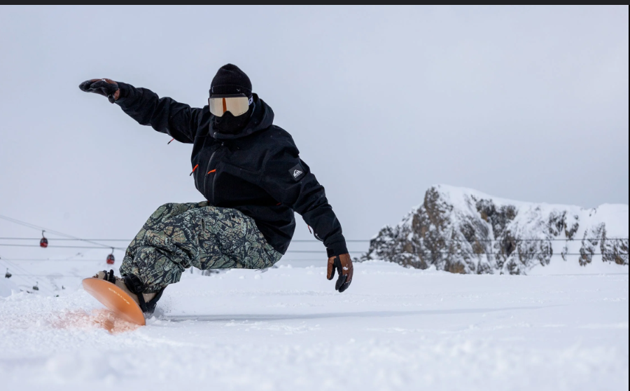 Snowboarder riding through powdery snow